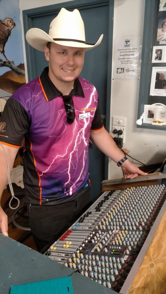 Tim mixing the sound for the live band using the sound board wearing cowboy hat