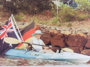 Giselle kayaking with two flags behind her on the kayak