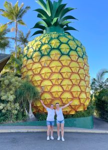 Reggie and woman standing in front of large pineapple that towers over them.