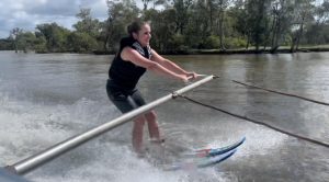 Reggie waterskiing looking ahead and holding onto a support bar coming off of boat.