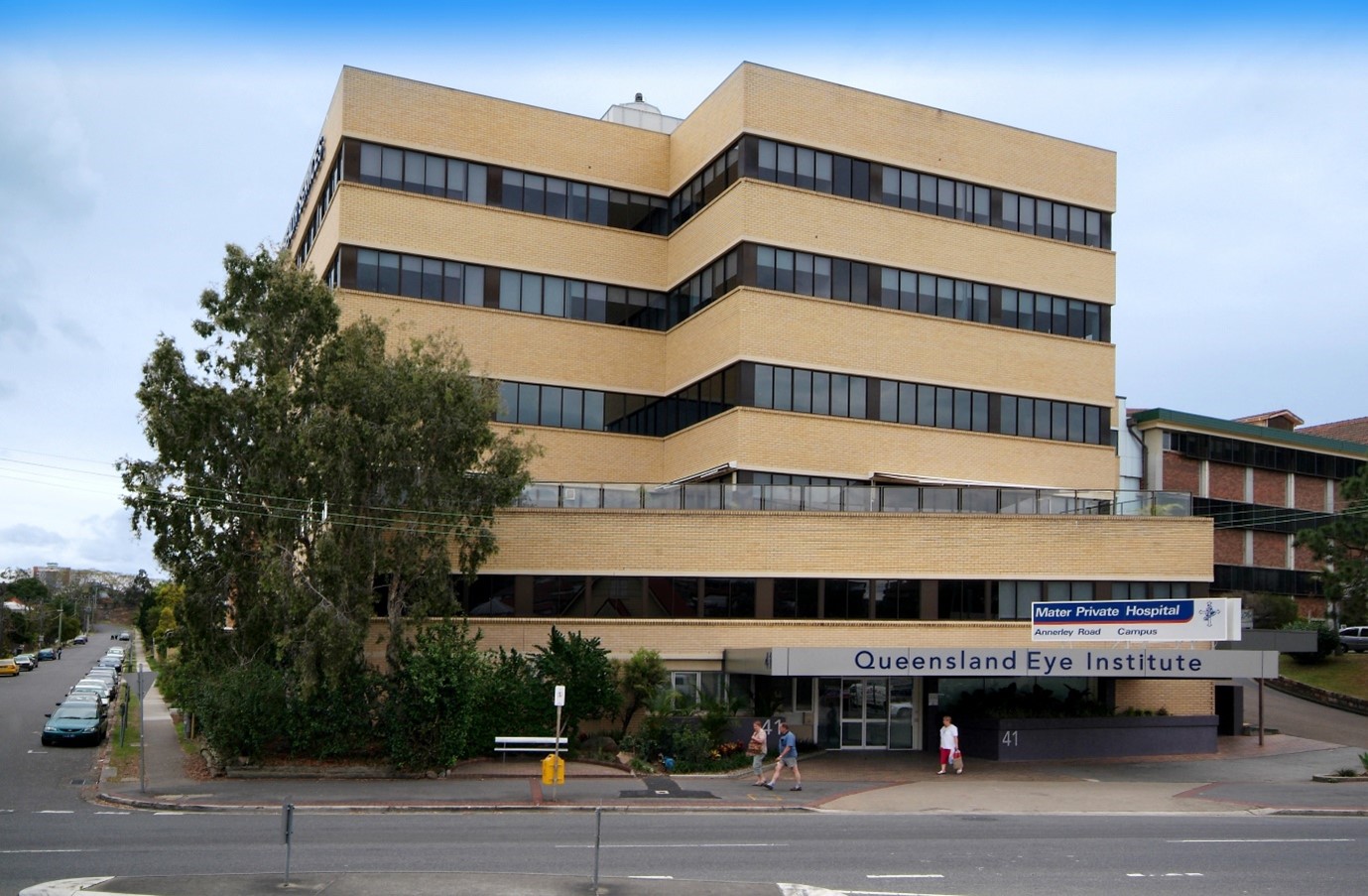 Large yellow brick building five storeys tall with a sign at front door reading "Queensland Eye Institute"