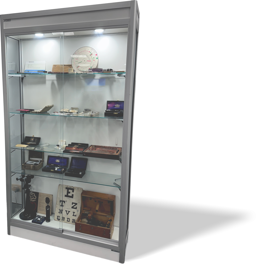 Aluminium cabinet with four glass shelves, glass doors and down lights, displaying old medical equipment